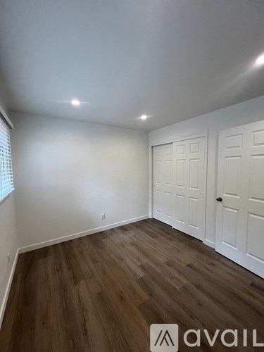 A room with wooden floors and white walls with two doors.