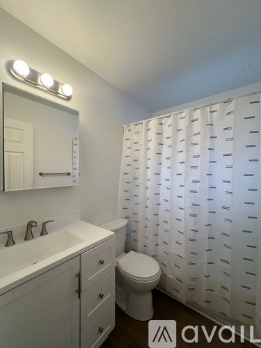 A bathroom with a toilet, sink, and a mirror.