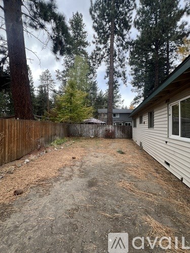A backyard with a wooden fence and a house in the background.