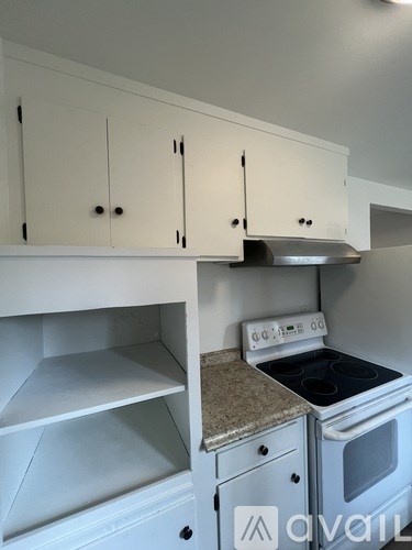 A kitchen with white cabinets and a stove top oven.