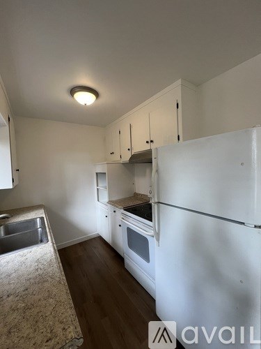 A kitchen with white appliances and wooden floors.