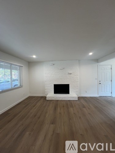 A room with a white fireplace and wooden flooring.