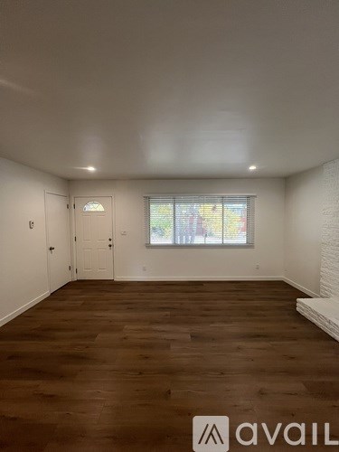 A room with wooden flooring and a window with a view of trees.