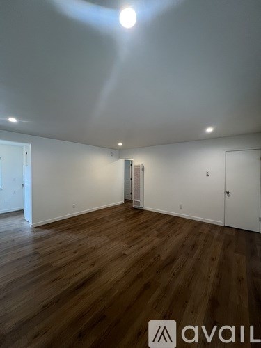 A room with wooden floors and white walls, with a logo that reads "avaiL" on the bottom right.