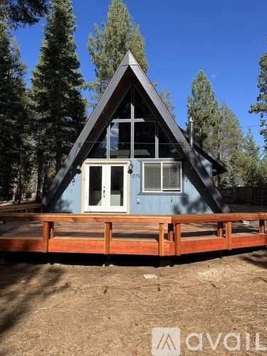 A blue house with a triangular roof and a deck in front.