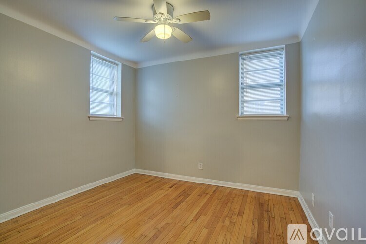 A room with wooden floors and two windows.