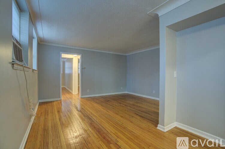 A room with wooden floors and a doorway leading to another room.