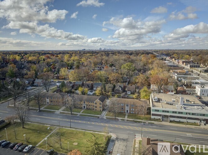 A view of a town with a large building in the foreground and a cloudy sky above.