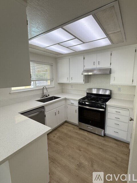 A kitchen with white cabinets and a stainless steel stove top oven.