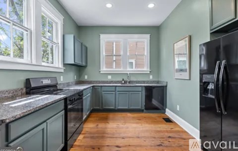 A kitchen with a black refrigerator and wooden floors.