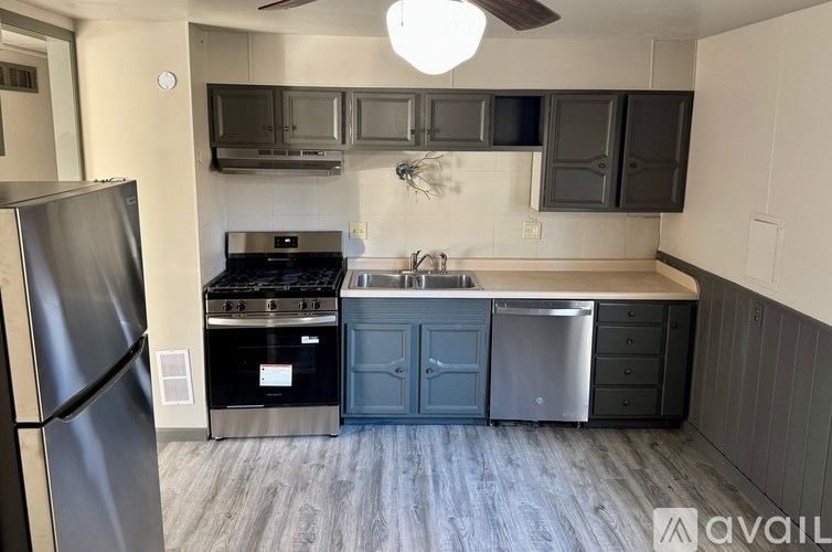 A kitchen with a refrigerator on the left and a sink with a dishwasher below it.