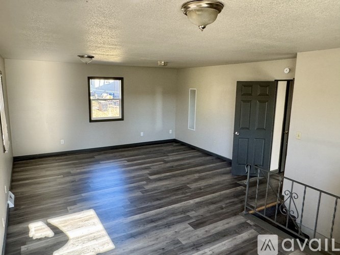 A room with wooden flooring and a black door.