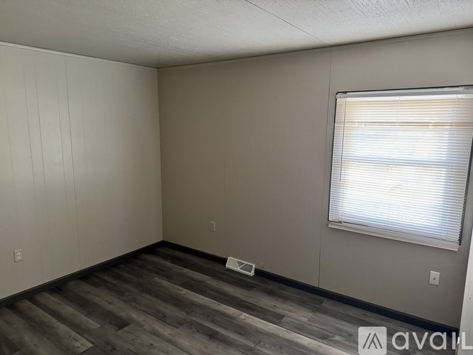A room with a window and wooden flooring.