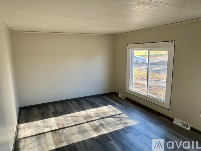 A room with a window and a wooden floor.