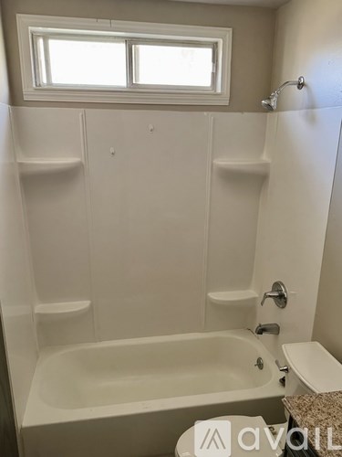 A white bathroom with a tub and a window.
