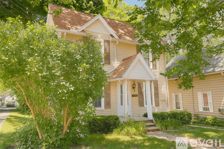 A house with a white door and windows surrounded by greenery.