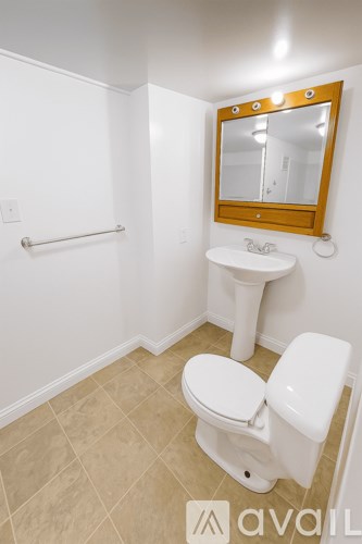 A bathroom with a toilet, sink and mirror.