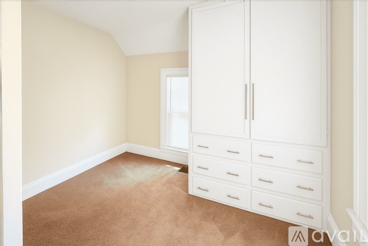 A room with a white wardrobe and drawers.