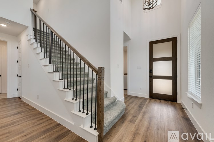 A staircase with a wooden handrail and white steps leads to a doorway.