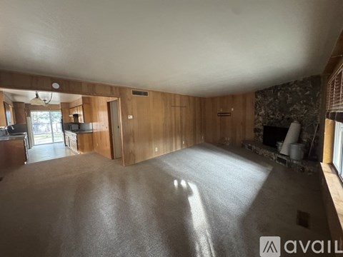 A spacious room with wooden walls and a stone fireplace.