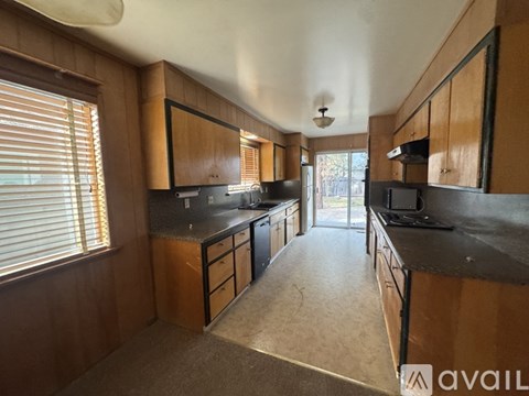 A kitchen with wooden cabinets and black countertops.