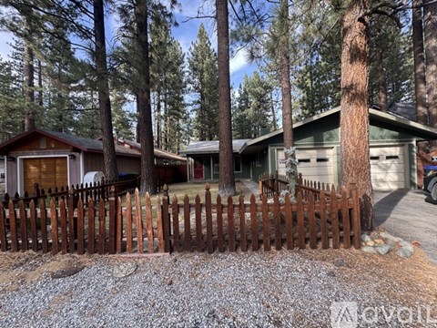 A wooden fence in front of a house with a tree growing out of it.