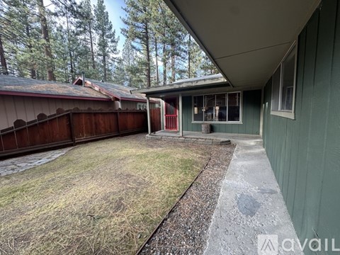 A backyard with a wooden fence and a green house.
