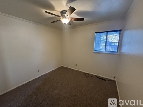 A room with a ceiling fan and a window with blinds.