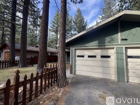A house with a green garage door is surrounded by a wooden fence.