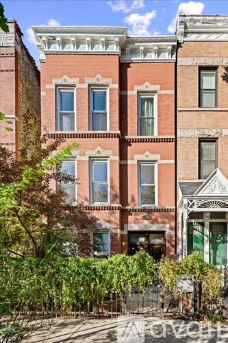 A row of red brick buildings with green plants in front.