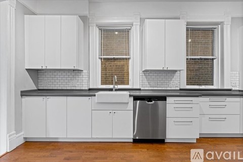 A kitchen with white cabinets and a black countertop.