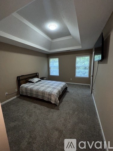 A bedroom with a bed, carpet, and a window.