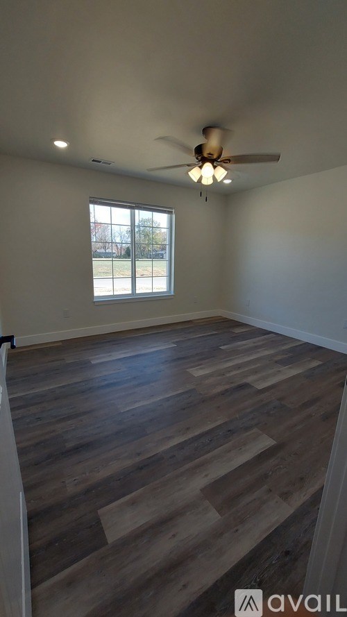 A room with wooden flooring and a ceiling fan.