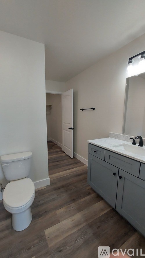 A bathroom with a toilet, sink, and wooden floors.