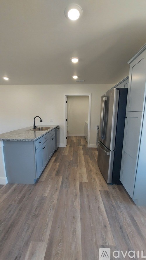 A kitchen with a sink, refrigerator, and cabinets.