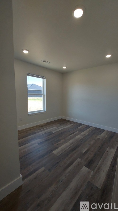 A room with wooden flooring and a window.