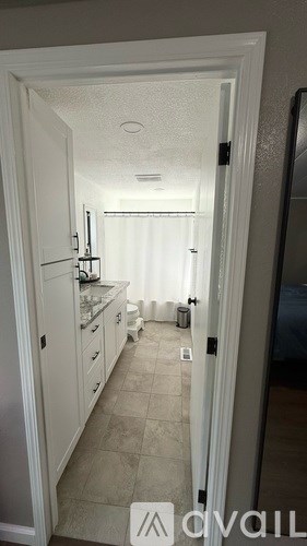 A hallway with a white door leading to a kitchen.