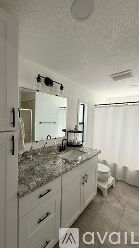 A bathroom with a granite countertop and white cabinets.