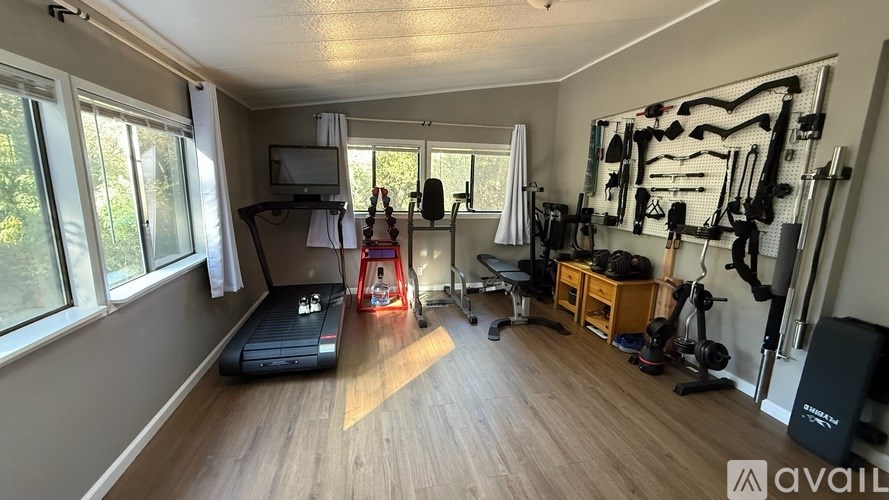 A well-equipped home gym with a treadmill, exercise bench, and various workout equipment.