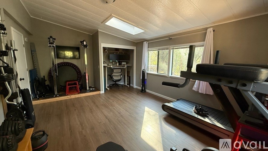 A room with a treadmill, exercise bike, and a piano.