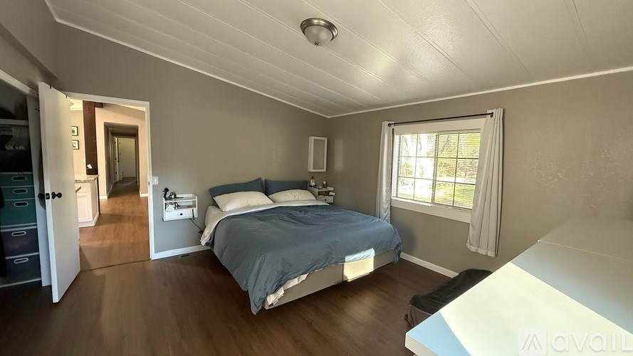A bedroom with a bed, nightstand, and window.