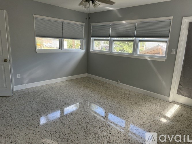 A room with a ceiling fan and three windows.