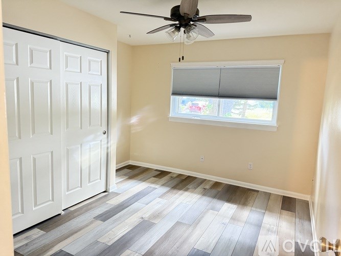 A room with a ceiling fan and a window with blinds.