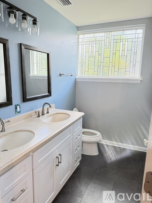 A bathroom with a sink, toilet, and window.