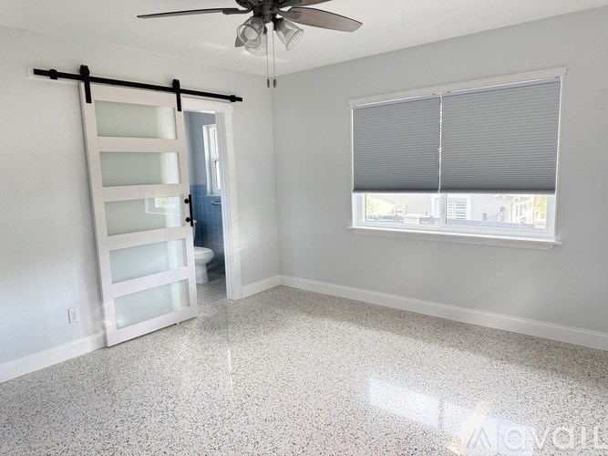 A room with a ceiling fan and a window with blinds.