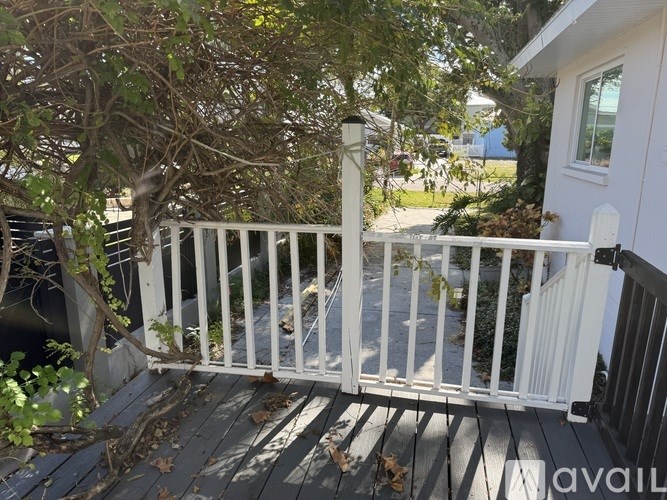 A white railing on a deck with a tree in the background.