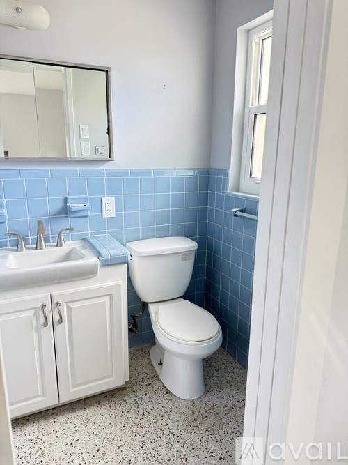 A white toilet sits in a bathroom with blue tiles.