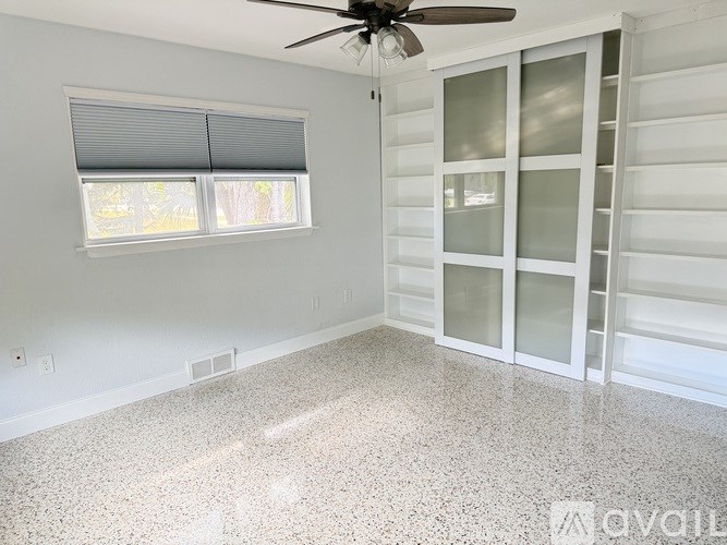A room with a ceiling fan and a window with blinds.