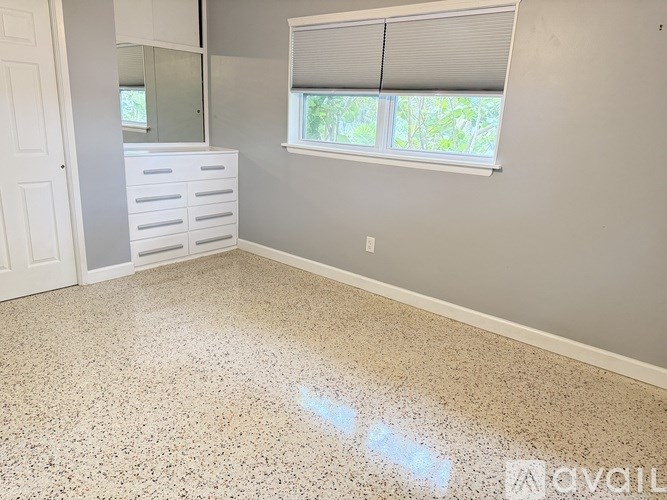 A room with a white dresser and a window with blinds.
