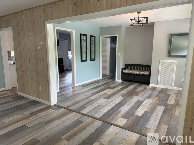 A room with wooden flooring and a bench in the corner.